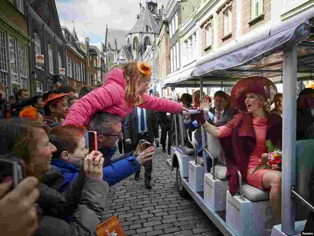 Ratu Maxima dari Belanda (kanan) menyapa kerumunan orang dalam sebuah parade Hari Raja di Dordrecht, Belanda.