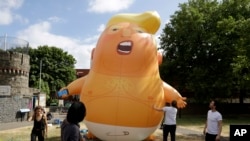 In this July 10, 2018, photo, a six-meter high cartoon baby blimp of U.S. President Donald Trump stands inflated during a practice session in Bingfield Park, north London.