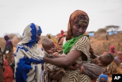 FILE - Basherow Hassen, a mother of four, waits for food aid with her twin children in the Warder district in the Somali region of Ethiopia, Jan. 28, 2017.