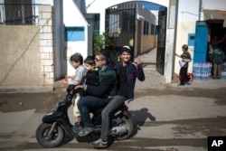 A boy gestures to the camera as he and his relatives leave school at Hara Kbira, the main Jewish neighborhood on the island of Djerba, southern Tunisia, Oct. 30, 2015..