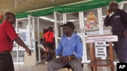 지난 1월 라이베이라 몬로비아의 정부 청사 출입구에서 보건 관계자가 통행하는 사람들의 에볼라 감염 여부를 검사하기 위해 체온을 재고 있다. 그 옆에는 "건물을 들어가기 전에 손을 씻어주세요" 라는 안내문이 붙어있다. 
