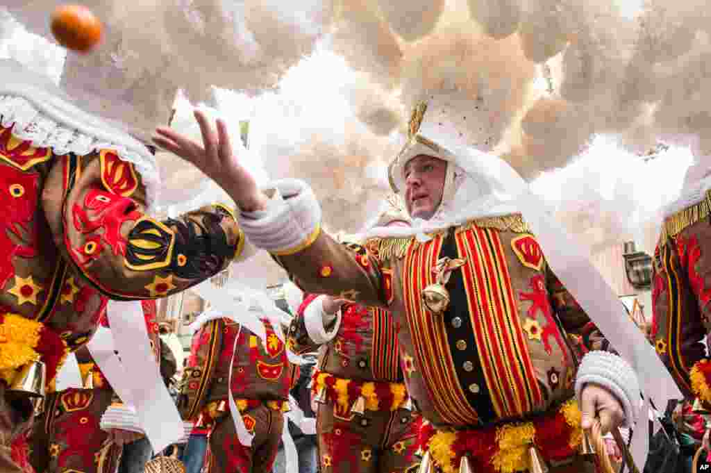 Seorang pria yang berpakaian seperti perempuan, yang disebut &#39;Gilles of Binche&#39; melempar buah-buah jeruk pada acara karnaval Binche di kota Binche, Belgia. Karnaval &#39;Binche&#39; di kota Binche ini diakui oleh UNESCO sebagai salah satu warisan budaya dunia.