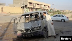 A resident inspects a damaged vehicle a day after a car bomb attack in Dujail, 50 kilometers north of Baghdad, Aug. 23, 2013.