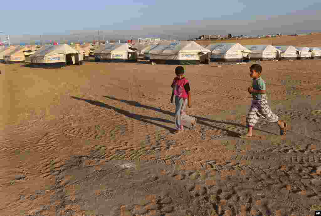 An Iraqi refugee child walks in front of a camp for displaced Iraqis who fled from Mosul and other towns, in Khazer, outside Irbil, northern Iraq, June 22, 2014.