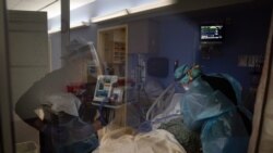 Registered nurses Kyanna Barboza, right, tends to a COVID-19 patient as Kobie Walsh puts on her PPE at St. Joseph Hospital in Orange, Calif. Thursday, Jan. 7, 2021. California health authorities reported Thursday a record two-day total of 1,042 coronaviru