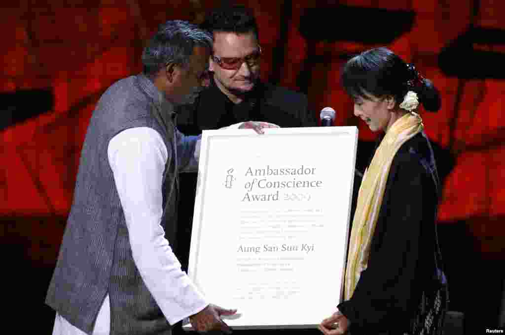 Aung San Suu Kyi accepts the Amnesty International Ambassador of Conscience Award from Amnesty International Secretary-General Salil Shetty (L) and singer Bono (R), Dublin, Ireland, June 18, 2012.