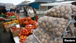 FILE - People walk past goods at the market in Suwalki, Poland, March 2009.