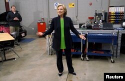 U.S. presidential candidate and former Secretary of State Hillary Clinton talks to reporters with a Secret Service agent looking on (L) in an auto shop as she campaigns for the 2016 Democratic presidential nomination at Kirkwood Community College in Monti