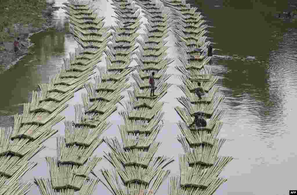 Para pekerja India membawa bambu-bambu melewati sungai Longai di kota Damchara, negara bagian Tripura.