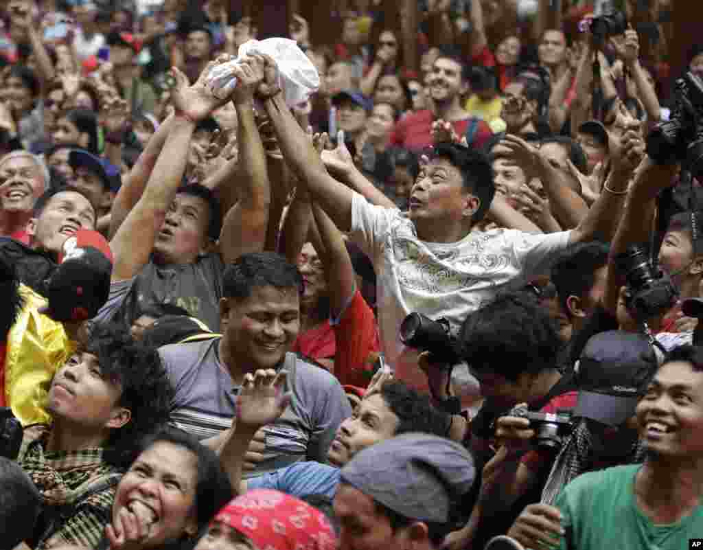 Revelers try to catch envelopes containing cash and other items being given away following a dragon and lion performances in front of a grocery store in Manila&#39;s Chinatown district of Binondo, Philippines, in celebration of Chinese New Year.