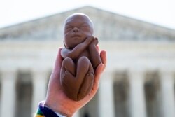 Seorang demonstran Pro-life mengangkat replika janin yang belum lahir saat menunggu putusan tentang aborsi di depan Mahkamah Agung AS di Washington, DC, pada 22 Juni 2020. (Foto: AFP/Jim Watson)