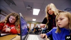 In this file photo taken Nov. 4, 2015, computer science teacher Sheena York, center, helps fifth grade students work on programming during their weekly computer science lesson at Marshall Elementary School in Marysville, Wash. (AP Photo/Elaine Thompson)