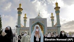 Worshippers wearing protective face masks offer Eid al-Fitr prayers outside a shrine to help prevent the spread of the coronavirus, in Tehran, Iran, Sunday, May 24, 2020