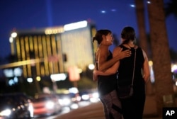 Madisen Silva, right, and Samantha Werner embrace at a makeshift memorial for victims of a mass shooting in Las Vegas, Oct. 6, 2017.