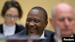 ປະທານາທິບໍດີ​ເຄັນ​ຢາ ທ່ານ Uhuru Kenyatta (ກາງ) ຍິ້ມເສີຍ ໃນຂະນະທີ່ນັ່ງຢູ່ ທ່າມກາງທີມທະນາຍຄວາມຕໍ່ສູ້ ຄະດີໃຫ້ທ່ານ ໃນເວລາປາກົດ​ໂຕ ​ຢູ່​ຕໍ່ໜ້າ ສານ​ອາ​ຊະຍາ​ກຳ​ສາກົນ ໃນນະຄອນ Hague, ວັນທີ 8 ຕຸລາ 2014.