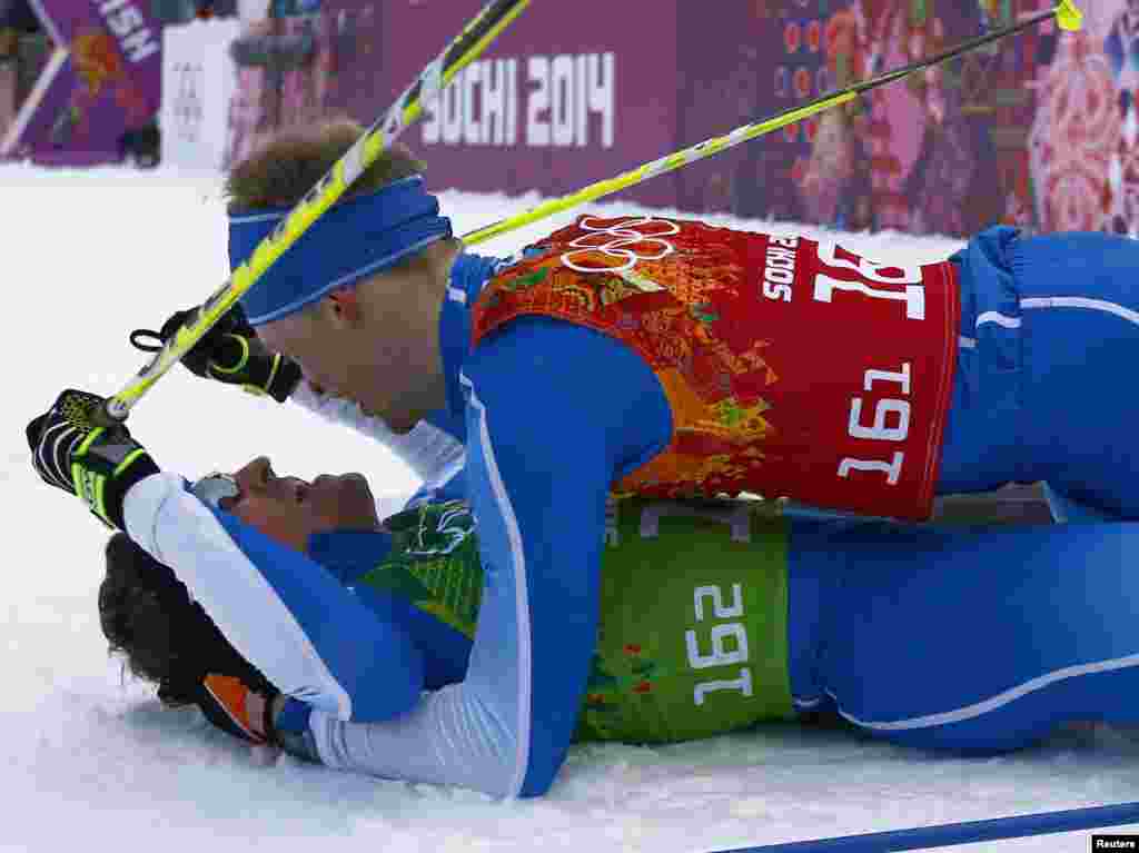 Finland's Sami Jauhojaervi and his team mate Finland's Iivo Niskanen (upper) celebrate after crossing the finish line in the men's cross-country team sprint classic fina, Sochi, Feb. 19, 2014.