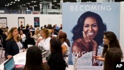 FILE - A poster for former first lady Michelle Obama's memoir, "Becoming," is displayed at the Penguin Random House exhibit, May 31, 2018, at Book Expo in New York. The book went on sale this month.