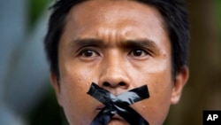 A Myanmar journalist with his mouth sealed with tape, symbolizing the government's recent crackdown on media, protest outside Myanmar Peace Center where President Thein Sein attends a meeting in Yangon, Myanmar, July 12, 2014. 