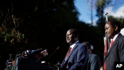 Kenya's opposition leader Raila Odinga, center, accompanied by party official Kalonzo Musyoka, right, announces they will challenge the results of last week's presidential election in the Supreme Court.