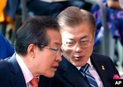 South Korean presidential candidates Hong Joon-pyo, left, of the Liberty Korea Party and Moon Jae-in of the Democratic Party confer as they attend a service to celebrate Buddha's birthday at the Jogye temple in Seoul, South Korea, May 3, 2017.