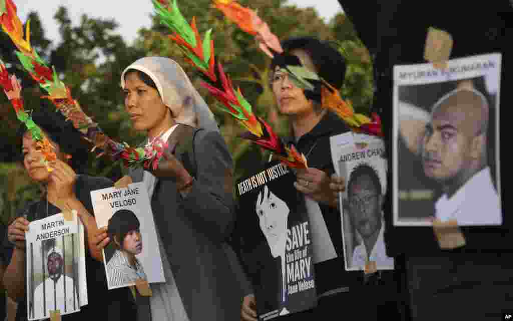 Aktivis Indonesia memegang foto tahanan, yang merupakan terpidana mati kasus narkoba, dalam sebuah demo yang menuntut pemerintah menghentikan eksekusi mereka, di Jakarta. Keluarga terpidana berkunjung untuk terakhir kalinya dan merupakan pertanda bahwa pemerintah segera mengeksekusi delapan orang asing dan seorang warga Indonesia, walaupun dunia internasional menolaknya dan meminta pengampunan bagi mereka.