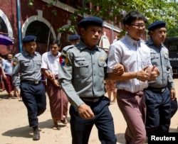 FILE - Reuters journalists Wa Lone, center front, and Kyaw Soe Oo, center back, are escorted by police as they return to their trial after a lunch break at the court in Yangon, Myanmar, April 20, 2018.