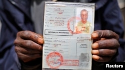 An African migrant shows his ID at a detention center in Zawiya, northern Libya, May 27, 2014.