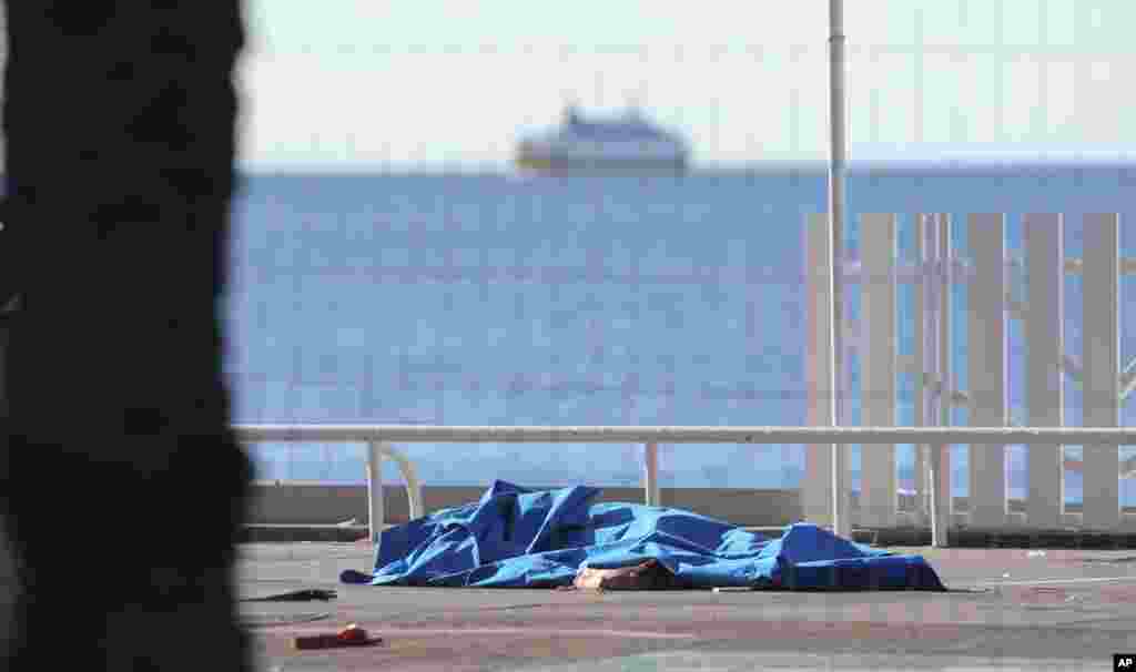 Bodies of victims covered by sheets at the scene of a truck attack in Nice, southern France, Friday, July 15, 2016. 