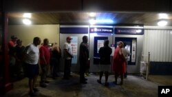 Clients of Popular Bank of Puerto Rico wait in line at the Carolina Shopping Court branch to withdraw cash from their accounts after the passage of Hurricane Maria, in Carolina, Puerto Rico, Sept. 27, 2017.