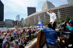 Sen. Elizabeth Warren, D-Mass., waves to the crowd from the back of a pickup truck prior to speaking at the Rally Against Separation, June 30, 2018, in Boston.