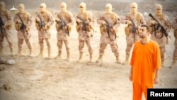 A man purported to be Islamic State captive Jordanian pilot Muath al-Kasaesbeh (in orange jumpsuit) stands in front of armed men in this still image from an undated video filmed from an undisclosed location made available on social media on February 3, 20