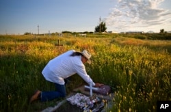 In this July 14, 2018, file photo, Kenny Still Smoking touches the tombstone of his 7-year-old daughter, Monica, who disappeared from school in 1979 and was found frozen on a mountain, as he visits her grave on the Blackfeet Indian Reservation in Browning