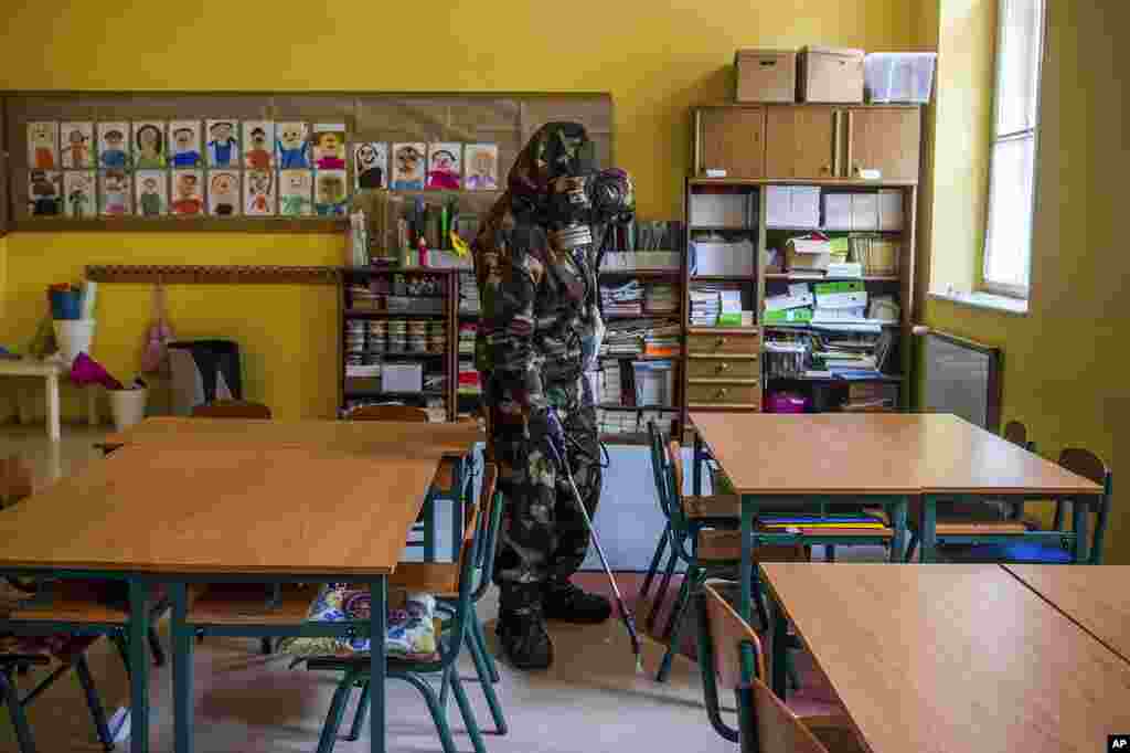 A Hungarian soldier wearing a hazmat suit disinfects a classroom of a combined kindergarten and elementary school in an effort to curb the spread of the pandemic of the new coronavirus in Budapest, Hungary.