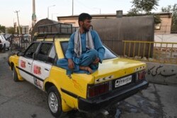 Seorang pengemudi menunggu penumpnag sambil duduk di atas bagasi taksinya di Kabul, 11 Agustus 2021.(Wakil KOHSAR / AFP)