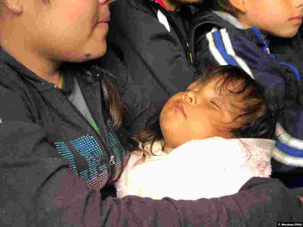 A migrant Guatemalan mother holds her infant child, who she said is sick with a cold. They are part of a group who turned themselves over to U.S. Customs and Border Patrol agents after crossing the border at Ciudad Juarez, Mexico, April 9, 2019. C. Mendoza/VOA News