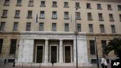 FILE - People walk past the Bank of Greece headquarters, in central Athens, March 27, 2015. 