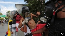 Un manifestante herido por una "metra" o canica disparada por las fuerzas de seguridad es ayudado por sus compañeros, durante una marcha realizada el lunes 29 de mayo.