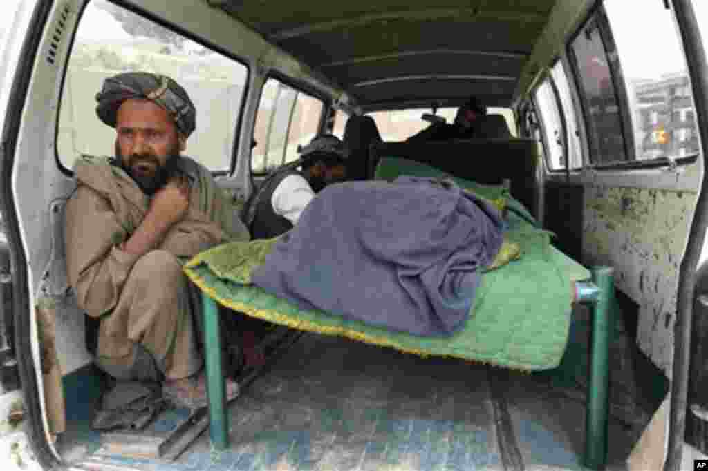 An Afghan man sits in the back of a bus with the body of a person who was allegedly killed by a U.S. service member in Panjwai, Kandahar province south of Kabul, Afghanistan, Sunday, March 11, 2012. Afghan President Hamid Karzai says a U.S. service member