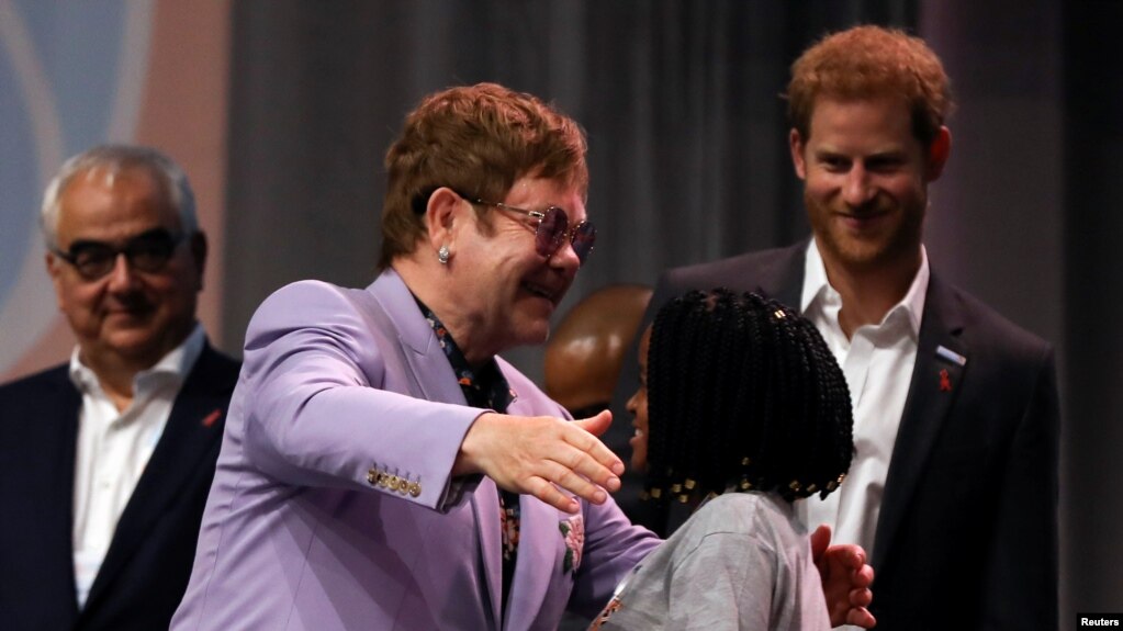 El mÃºsico britÃ¡nico Elton John abraza a un participante mientras el prÃ­ncipe Harry ve durante un panel "Rompiendo barreras de inequidad en la respuesta al VIH" durante la 22Âª Conferencia Internacional de SIDA (AIDS 2018), en Amsterdam, PaÃ­ses Bajos, 24 de julio de 2018.