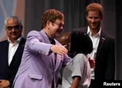 British musician Elton John embraces a participant as Britain's Prince Harry looks on during a panel "Breaking barriers of inequity in the HIV response" during the 22nd International AIDS Conference (AIDS 2018), the largest HIV/AIDS-focused meeting in the world, in Amsterdam, Netherlands, July 24, 2018.