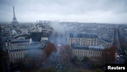 Para pengunjuk rasa mengenakan rompi kuning, simbol protes para pengendara Perancis terhadap kenaikan pajak solar, berdemonstrasi di Place de l'Etoile, Paris dengan latar belakang menara Eiffel, Perancis, 1 Desember 2018. (Foto: dok).