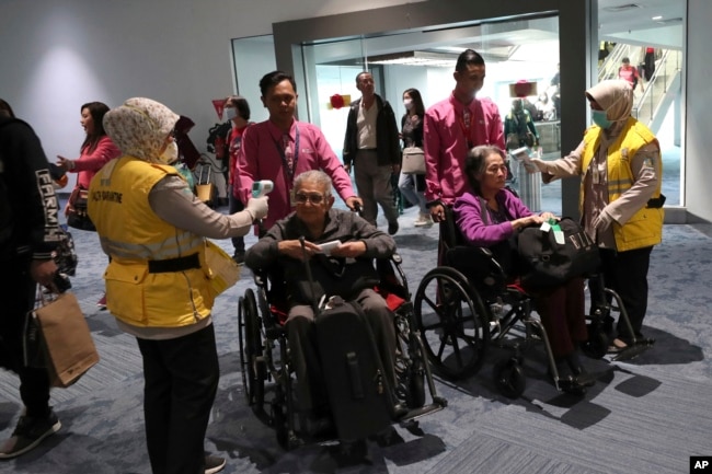 Petugas kesehatan memindai suhu tubuh penumpang saat tiba di Bandara Internasional Soekarno-Hatta di Tangerang, Rabu, 22 Januari 2020. (AP)