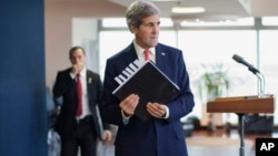 U.S. Secretary of State John Kerry picks up his notebook after answering questions from members of the media before his departure from Ben Gurion International Airport in Tel Aviv, Dec. 6, 2013.