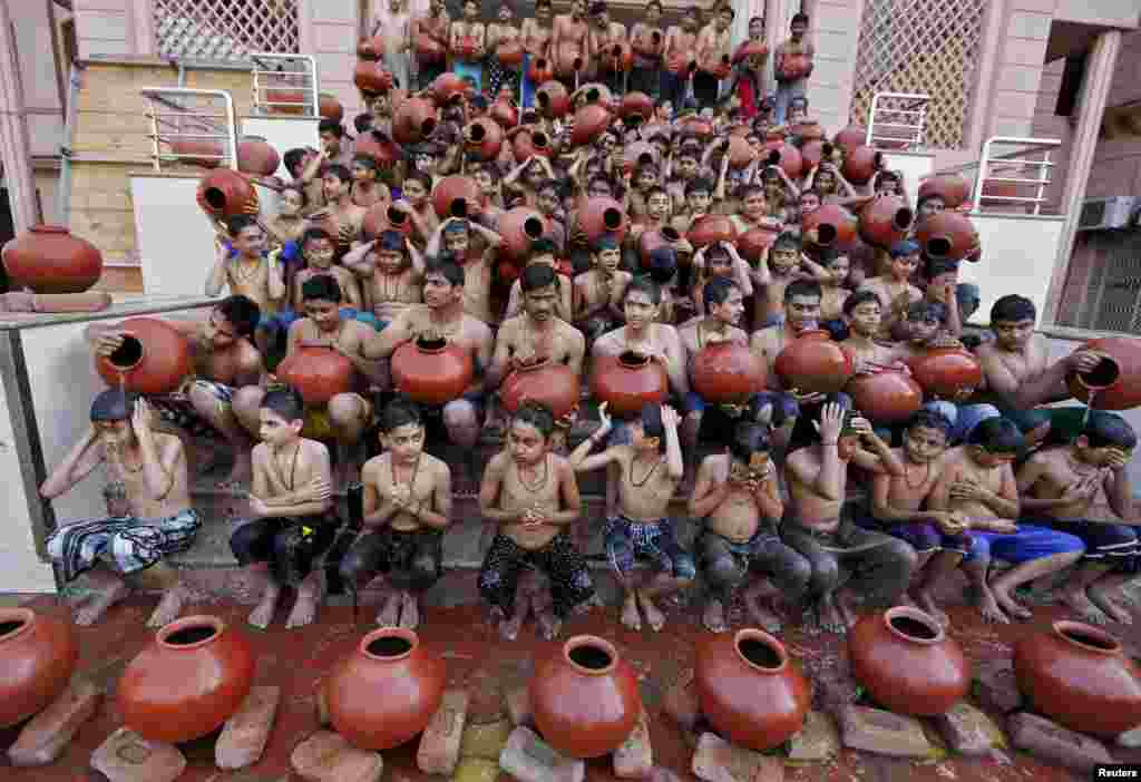 Những học sinh cầm những cái vại bằng đất đựng nước trong khi họ thực hiện nghi thức tắm linh thiêng trước lễ hội Magh Mela trong một buổi lễ tại thành phố Ahmedabad, Ấn Độ.