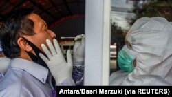 Petugas medis mengambil sampel usap dari seorang petugas untuk mencegah penyebaran Covid-19 di Palu, Provinsi Sulawesi Tengah, 3 Juni 2020. (Foto: Antara/Basri Marzuki via REUTERS)