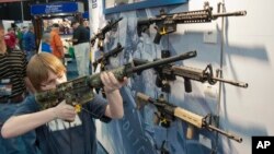 A young man, who chose not to give his name, sizes-up an assault style rifle during the National Rifle Association's annual convention in Houston, Texas, May 3, 2013. 