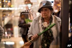 A woman watches demonstrators taking part in a protest outside a hotel where the newcomer to Spanish politics, the far-right Vox party holds a rally in Murcia, Spain, Nov. 14, 2018. Vox is reaching out to the neglected, working-class suburbs and rural areas with high unemployment, with polls predicting the Eurosceptic, anti-feminist and staunchly patriotic party on track to enter the country’s parliament in elections due before 2020.