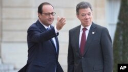 El presidente colombiano, Juan Manuel Santos y el presidente francés, Francois Hollande, firman acuerdos al final de su reunión en el Palacio del Eliseo en París, el lunes 26 de enero de 2015.