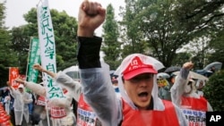 Protesters shout an anti-security bills slogan during a rally in rains in front of the Parliament building in Tokyo Thursday, Sept. 17, 2015. 