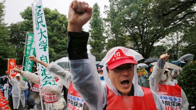 Protesters shout an anti-security bills slogan during a rally in rains in front of the Parliament building in Tokyo Thursday, Sept. 17, 2015.